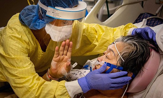 Jade Robinson embraces her mother, Thong Sengphirom, as she is treated for COVID-19 in the ICU at Mary Greeley on Dec. 10. As she leans in, her
mother reflexively reaches up to touch her and hits her face shield instead.