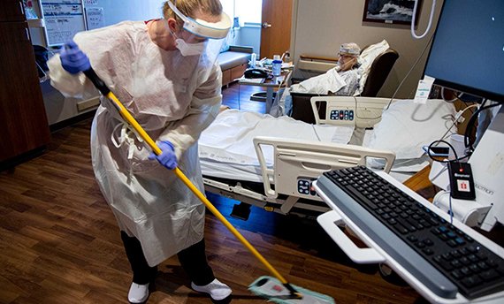Sherry Weitzel cleans the floor of COVID-19 patient Jan Beeghly’s room on Dec. 9, 2020, at Mary Greeley. Weitzel showers as soon as she gets home and keeps her shoes in the garage, frightened that her dogs might lick the treads, then swipe her family’s hands or faces.
